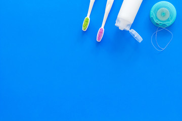 Set for daily teeth care. Toothbrush, tooth paste, dental floss on blue background top view copy space