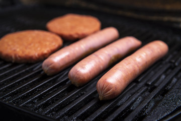 Fresh uncooked barbecue sausages, burgers and bread