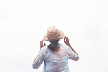 Rear view of woman in shirt, casual clothing with straw hat looking to the sky. Travel lifestyle concept