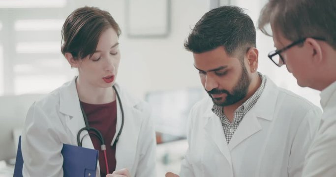 Closeup medical team, two men and one woman standing and talking in medical clinic. Team of doctors of medical center discuss diagnosis of the patient