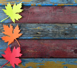 Fototapeta premium Yellow and red paper maple leaf on wooden background. Hello Autumn concept. Handmade crafts. Children's DIY. Copy space.