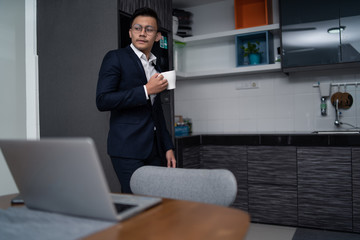 asian malay man working at home with laptop and calculator