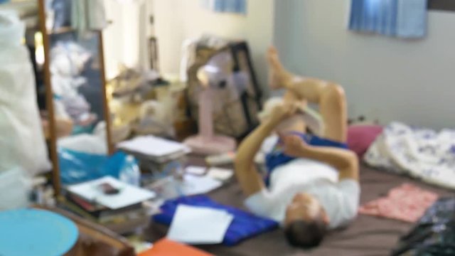 Defocus of man lying and reading book in messy room