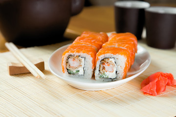 Sushi rolls with salmon and hot tea ceremony on table at home.Delivery of food at home.