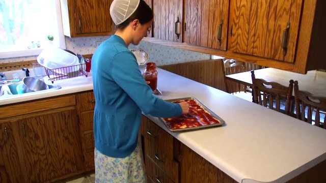 A young Mennonite woman prepares food in slow motion.
