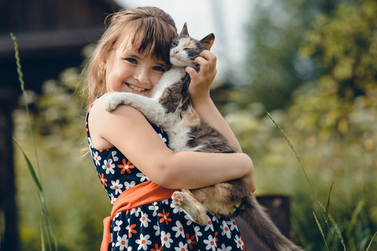 girl in a dress hugs a little cat
