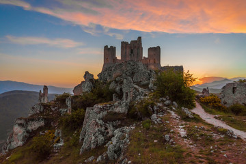 Fototapeta premium Rocca Calascio (Italy) - The ruins of an old medieval village with castle and church, over 1400 meters above sea level on the Apennine mountains in the heart of Abruzzo, at sunset.