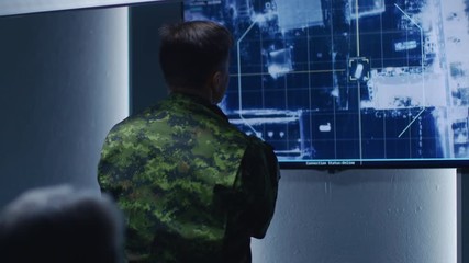 Military Man / Army Officer Watches Satellite Surveillance Footage / Car Tracking of the Target on Wall TV Screen. Secret Military Spying Operation in the Surveillance Center / System Control Room.