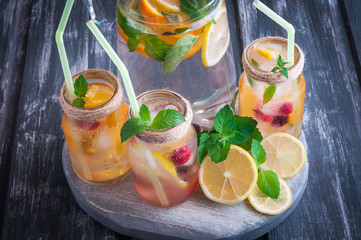 Lemonade with citrus, mint and berries in original Mason Jar. On a wooden background