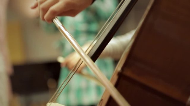 Close-Up of the strings of a cello played by a kid during a rehearsal on a music school.