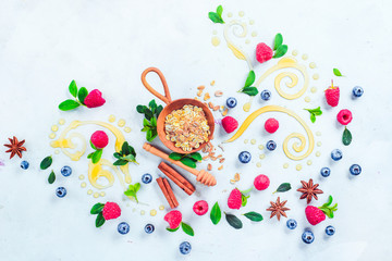 Oatmeal with honey, cinnamon, and berries. Raw ingredients with decorative honey swirls on a white wooden background with copy space