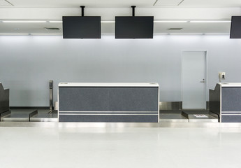 Empty desk in international airport at check-in counter with loading baggage area on background.