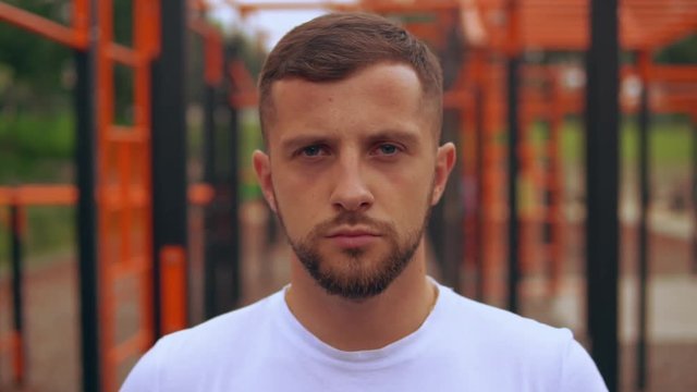 close-up of a young male looking directly. bearded caucasian guy wears white t-shirt.
