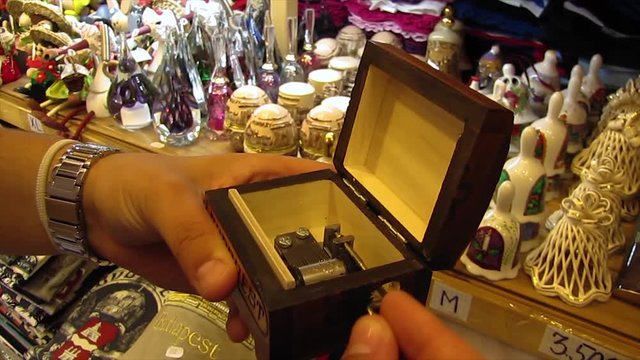 Person Playing a Manual Music Box in a Souvenir Shop.