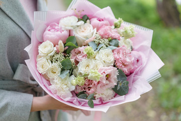 Young girl holding a beautiful spring bouquet. flower arrangement with peonies. Color light pink. The concept of a flower shop, a small family business