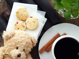 Overhead shot, teddy bear, coffee in white cup and saucer with shortbread and cinnamon	