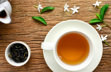 Cup of hot green tea with dried tea leaves in white cup and wood background. Chinese green tea known as healthy hot drink with antioxidant, also help with decrease fat in blood.