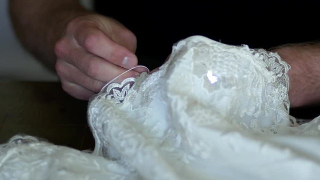 A beautiful dress are sewn by man's hands