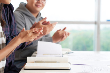 Cropped image of students clapping to speaker in class