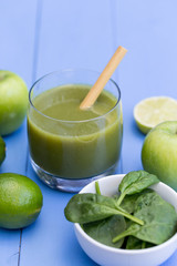 Healthy green smoothie drink with straw blue table background