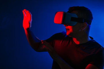 Scared young man in vr 3d glasses on dark background with red blue lighting