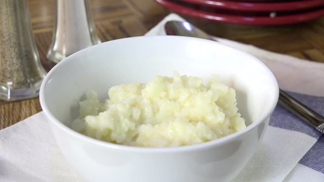 Spooning mashed cauliflower into a bowl, slow motion