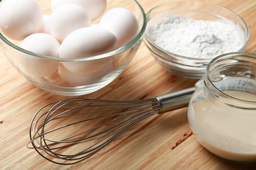 Fototapeta na wymiar Eggs, Flour, Yeast And Scutcher On Wooden Table Close-up