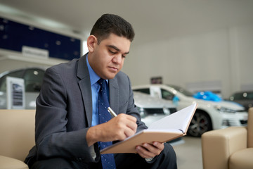 Serious multi-ethnic business executive checking his planner and taking notes