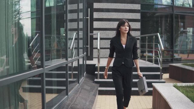 beautiful business woman in a strict suit and with a folder for papers goes near the business center