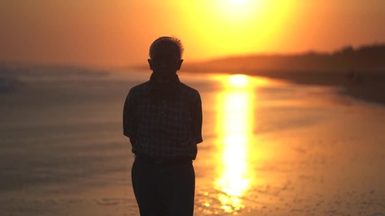 Silhouette of senior man walking on the beach at sunset time. Shot in 4k resolution - Powered by Adobe