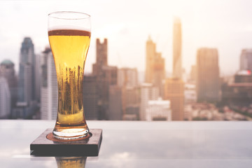 Glass of beer on table in rooftop bar in Bangkok