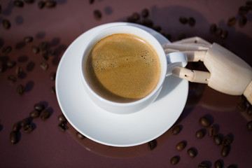 Cup of coffee with wooden hand on brown background