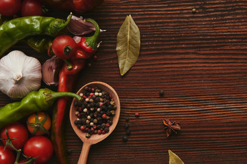 top view of wooden spoon with peppercorns and fresh vegetables on table