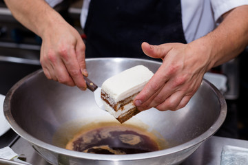 Close-up of tiramisu being soaked in coffee.