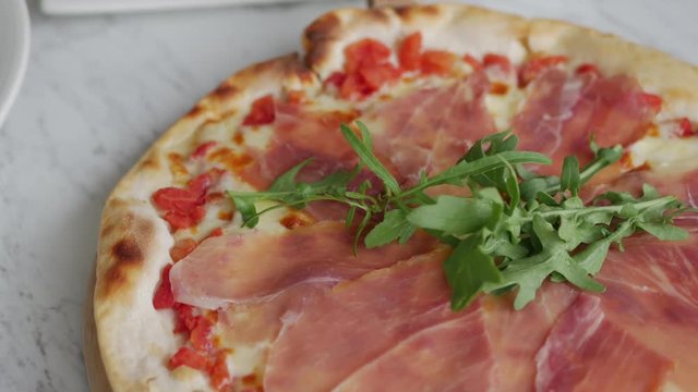 Traditional Italian fresh Prosciutto parma ham pizza serving on restaurant table.