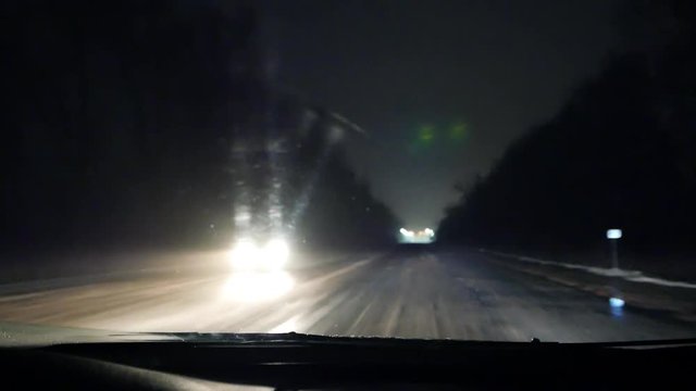 Night driving in the car on the wet snow bad road. Bad weather. Low beam and high beam of headlighs. Road safety