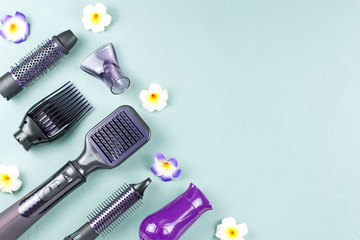 Hairdressing tools with flowers on blue wooden background