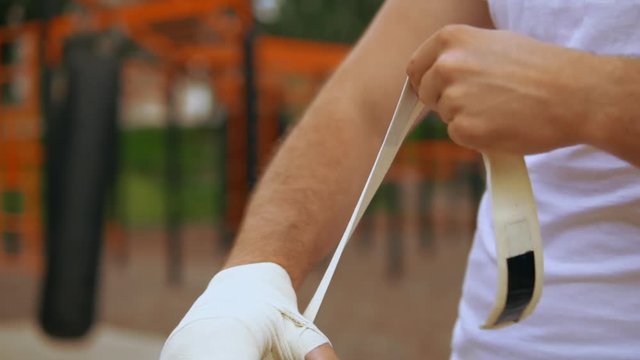 athlete using elastic bandage. he covers his hand roller-bandage.