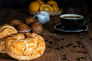 Naklejka na ściany i meble Breakfast set of hot coffee with croissant, banana cake and fresh orange fruits on wooden table with dark background