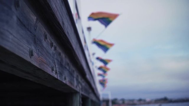 Out of focus pride flag from below a wooden dock in slow motion pan