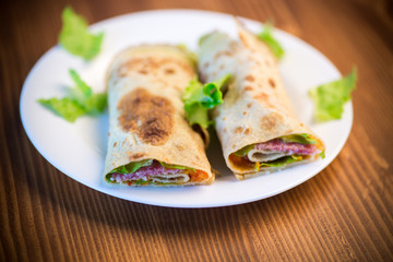 thin pancakes with salad leaves and bacon in a plate