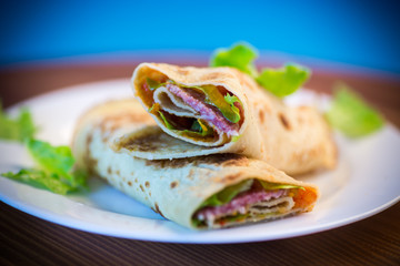 thin pancakes with salad leaves and bacon in a plate
