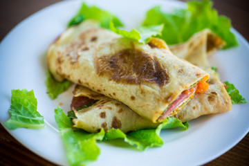 thin pancakes with salad leaves and bacon in a plate