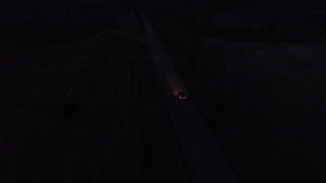 Aerial drone tracking shot of a 4x4 driving in night on a gravel road
