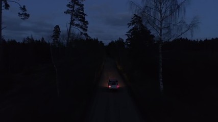 Aerial drone tracking shot of a 4x4 driving in night on a gravel road