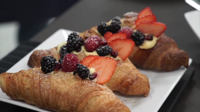 Delicious cream croissants with red fruits on top.