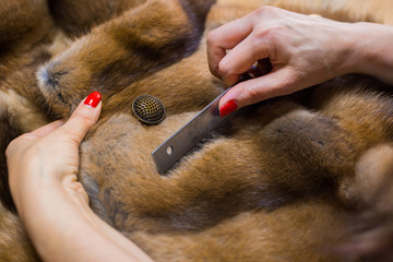 Professional tailor, designer combing fur coat at atelier, studio. Fashion and tailoring concept