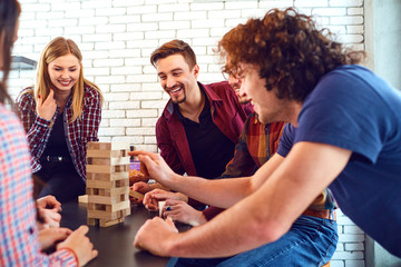 A cheerful group of young people play board games in the room.
