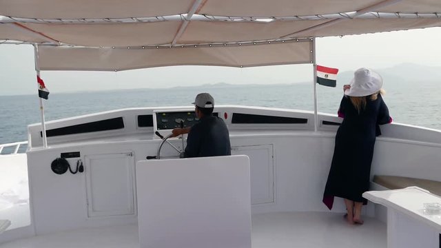 Sharm El Sheikh, Egypt- January 8, 2018: Sea voyage by yacht. Romantic tourist female and the captain helmsman on the deck of ship. Rest in a sea trip