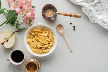 top view of bowl of cereal with coffee and flowers bouquet on white